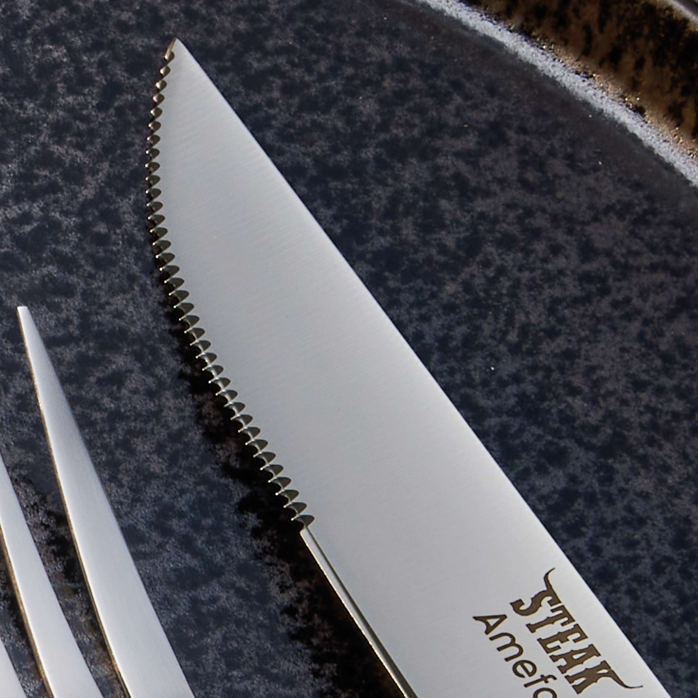 Amefa Porterhouse Steakbesteck Set aus 4 Teilen mit Holzgriff, Messer, Gabel und Löffel auf dunklem Hintergrund.