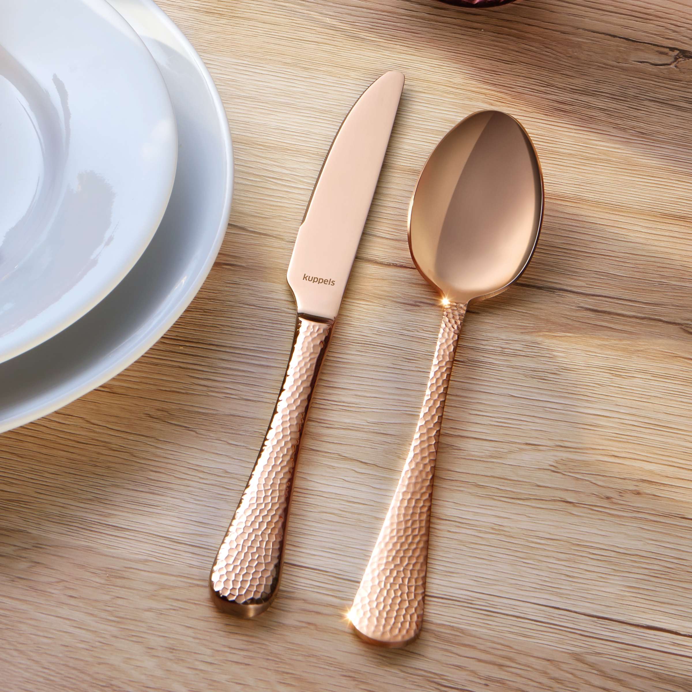 Elegantes 30-teiliges CRYSTAL Besteckset von Kuppels Home aus PVD rosé, glänzendes Messer, Gabel und Löffel auf dunklem Hintergrund.