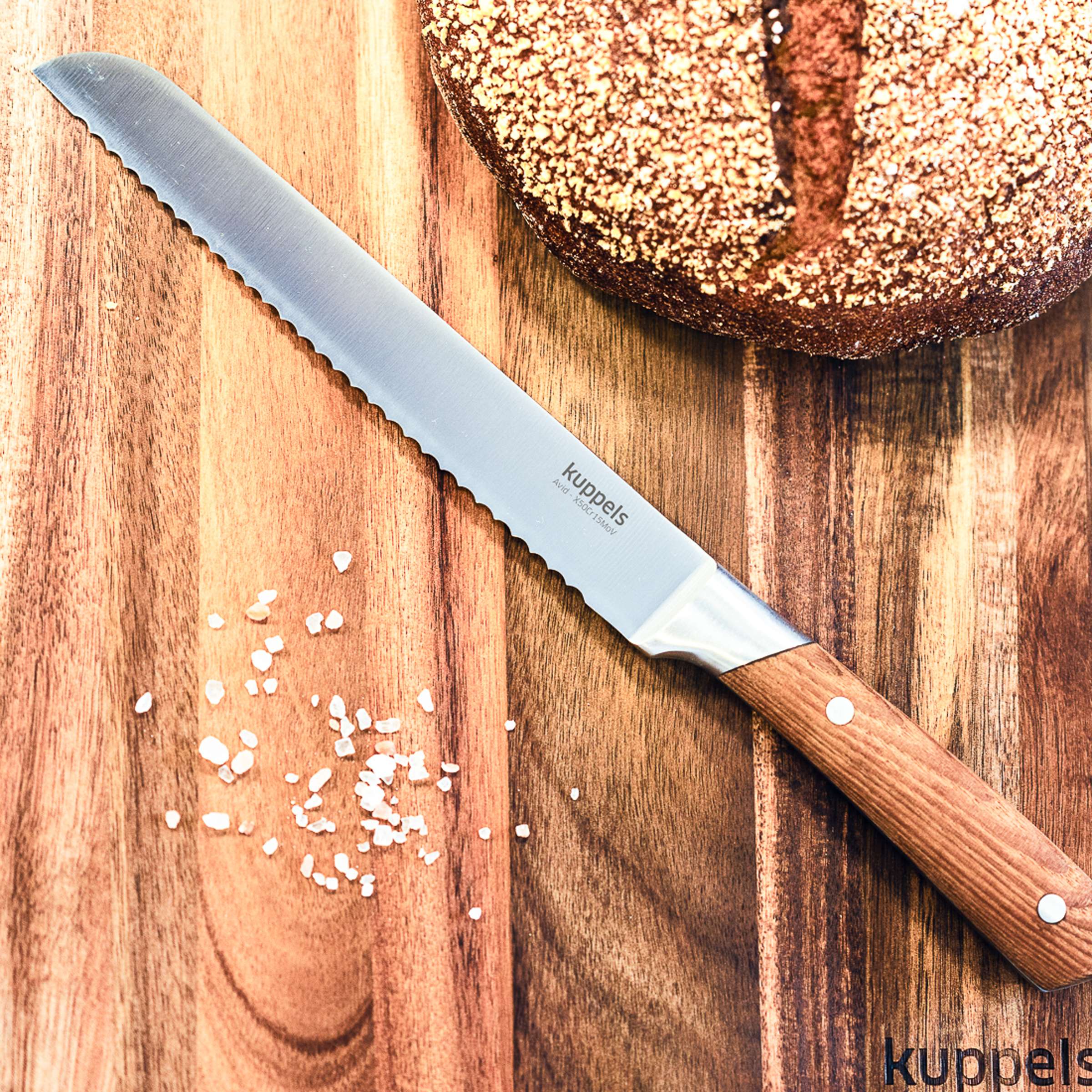 Kuppels AVID Brotmesser, scharfes Küchenmesser mit Wellenschliff, liegt auf Schneidebrett, ideal zum Schneiden von Brot.