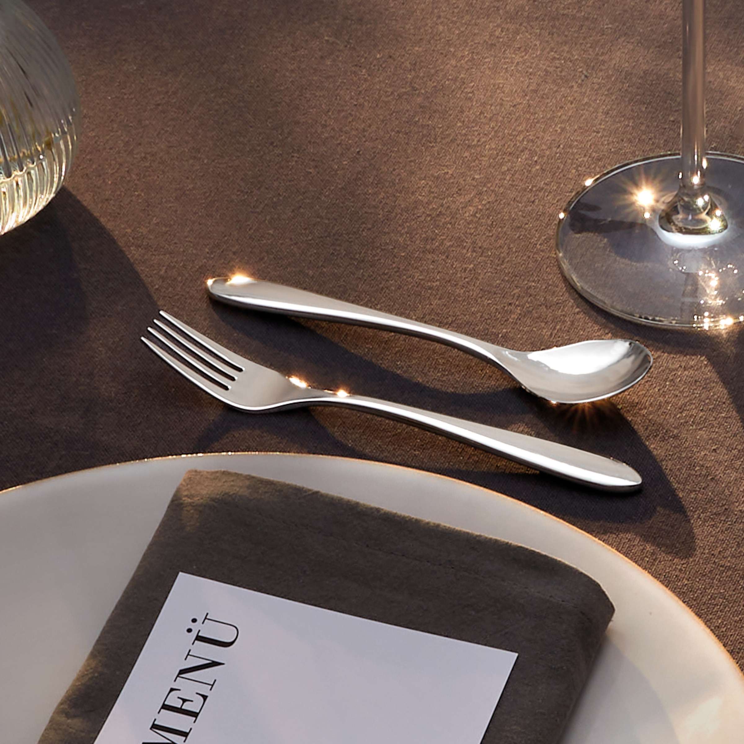 Amefa Cuba Besteckset 24-teilig mit Messer, Gabel, Löffel und Teelöffel aus Edelstahl, elegant auf einem gedeckten Tisch.