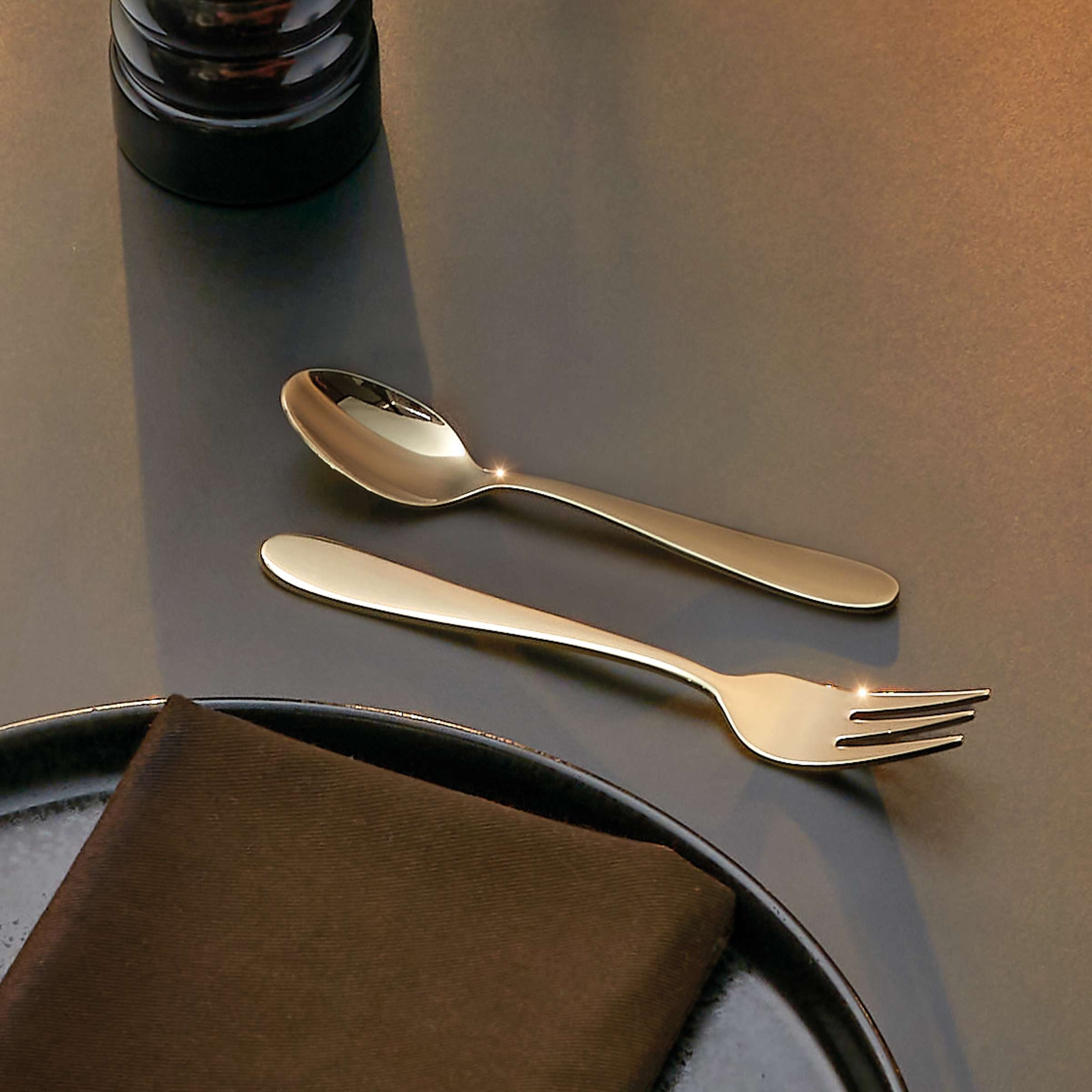 Oxford Besteckset 24-teilig von Amefa, PVD champagner, Besteck mit eleganten Griffen, komplett auf einem gedeckten Tisch.
