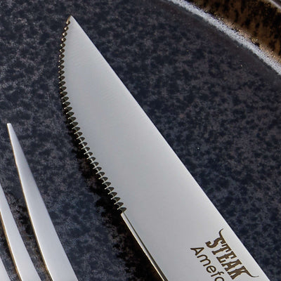 Amefa Porterhouse Steakbesteck Set aus 4 Teilen mit Holzgriff, Messer, Gabel und Löffel auf dunklem Hintergrund.