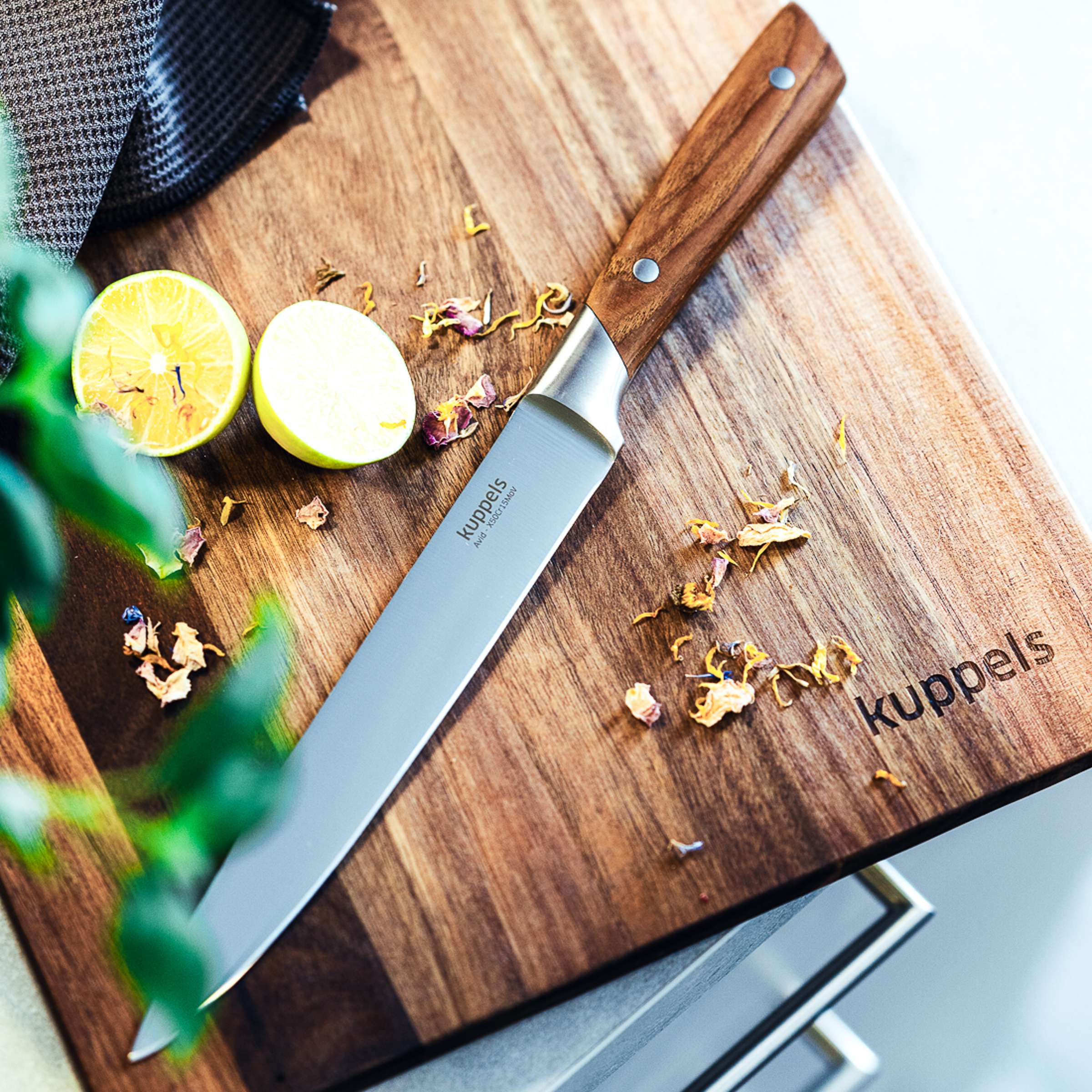 Ein Kuppels AVID Tranchiermesser aus Edelstahl, liegt auf einem Holzbrett, bereit zum Schneiden von Fleisch.