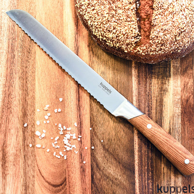 Kuppels AVID Brotmesser, scharfes Küchenmesser mit Wellenschliff, liegt auf Schneidebrett, ideal zum Schneiden von Brot.