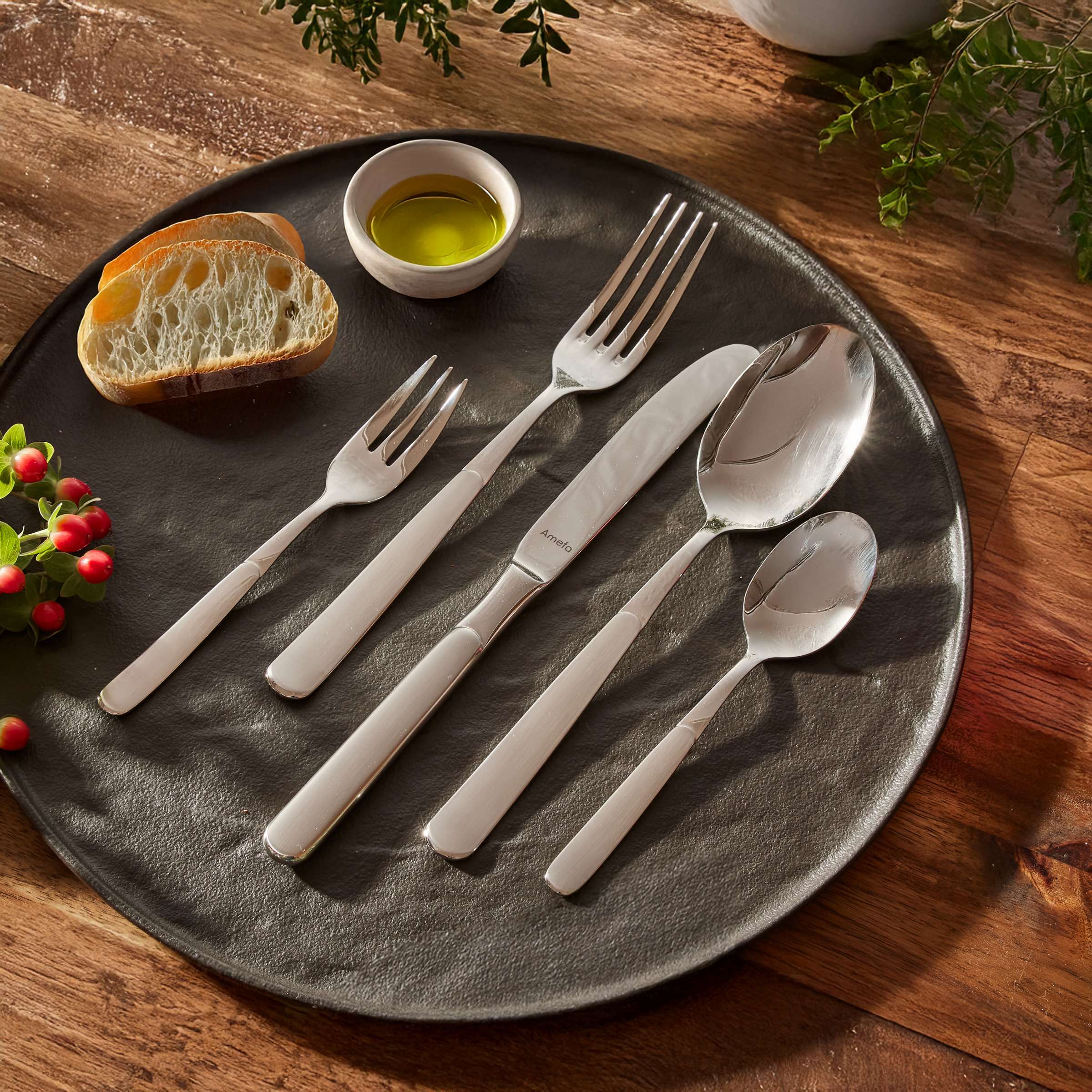 Amefa Satina Besteckset, 60-teilig, mattierte Edelstahl-Gabeln, Messer, Löffel auf einem gedeckten Tisch.